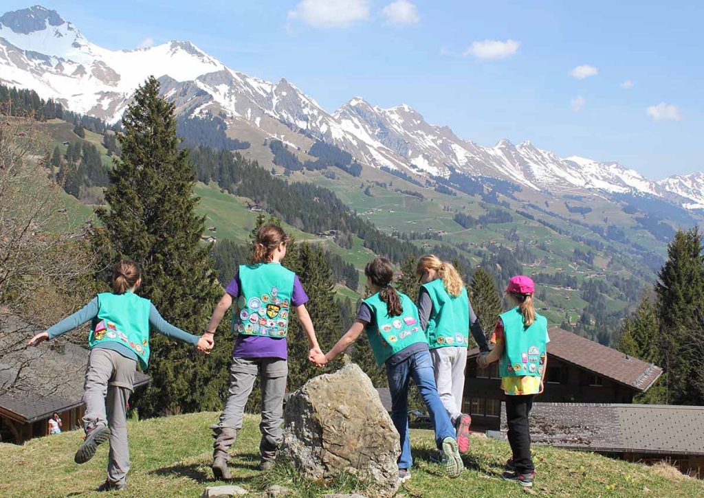 Girl scouts holding hands with mountains ahead