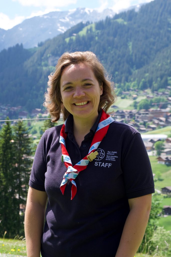 Our Chalet staff member in uniform with mountains in background