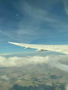 Tip of an airplane wing over a partially cloudy sky.