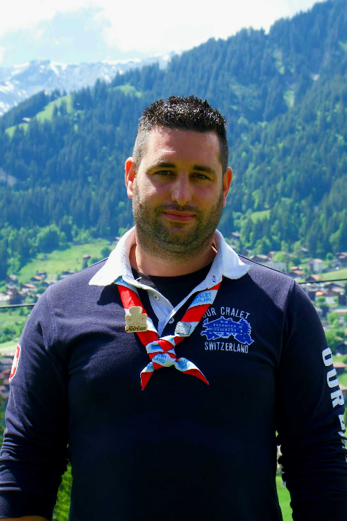 Our Chalet staff member Adrian in uniform with mountains in the background