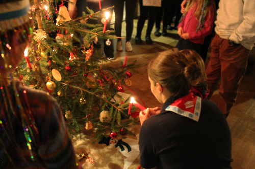 A staff member lighting a candle on the christmas tree